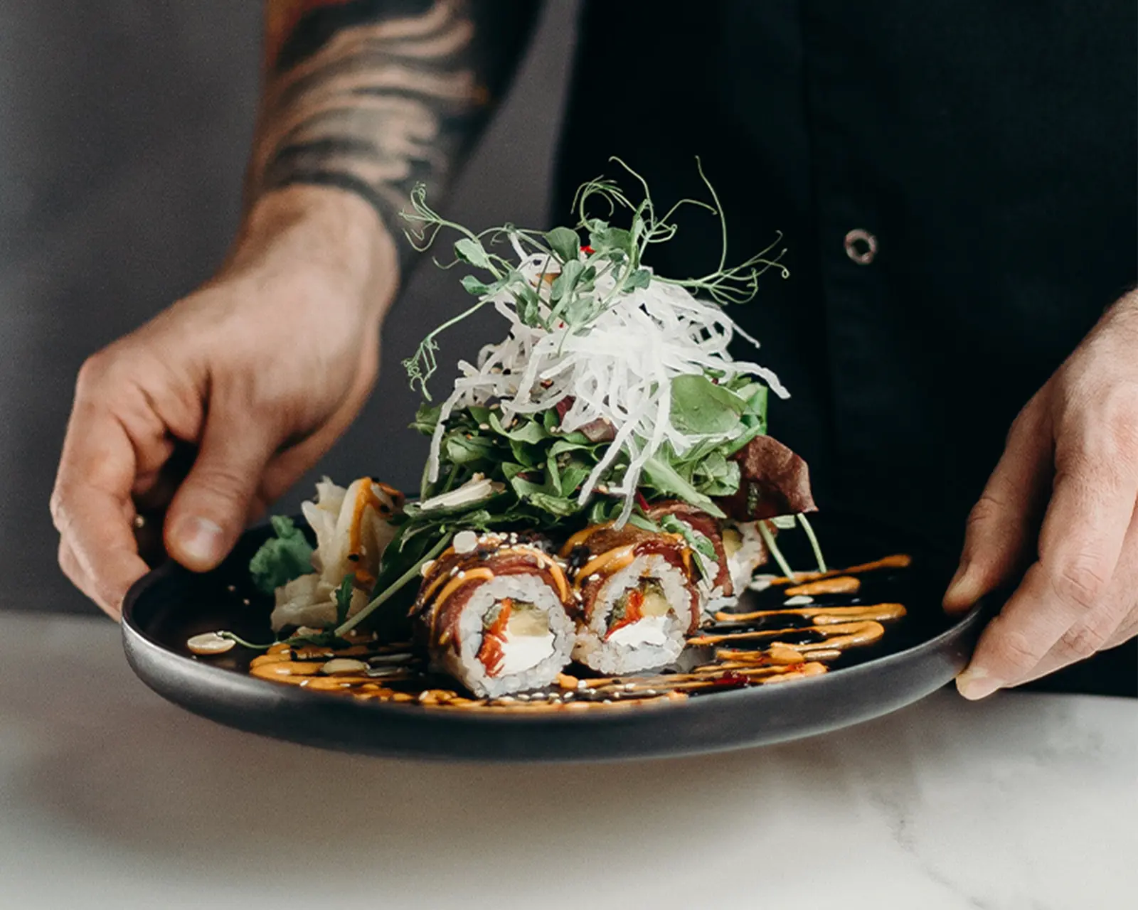 Chef présentant une assiette de sushis