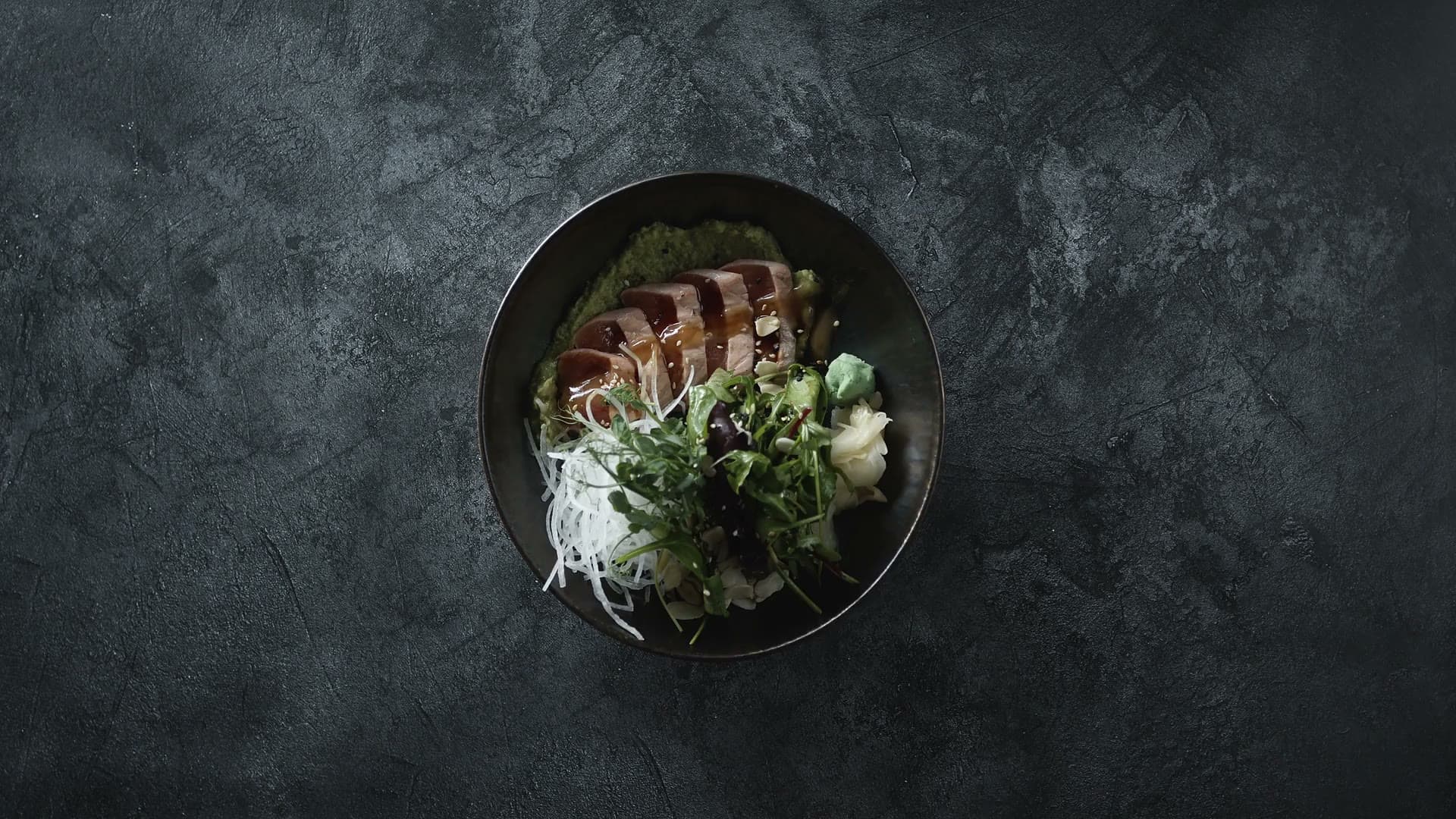 Bol de sashimi de thon mi-cuit vu de dessus, avec des baguettes