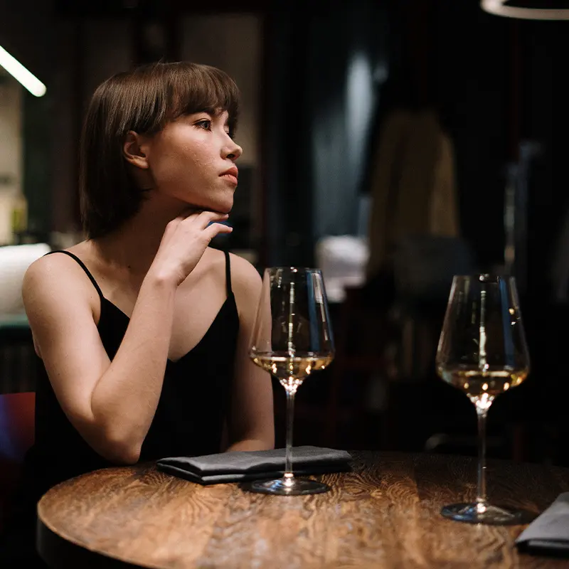 Cliente attablée à la lueur des bougies, un verre de vin à la main